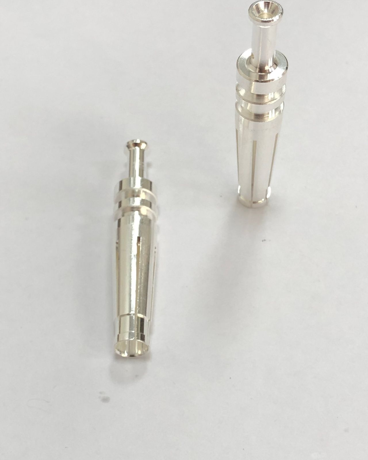 Two silver-plated socket contacts on white paper